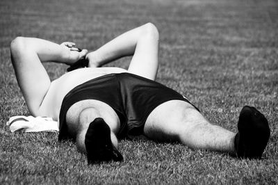 Low section of shirtless man lying on grass