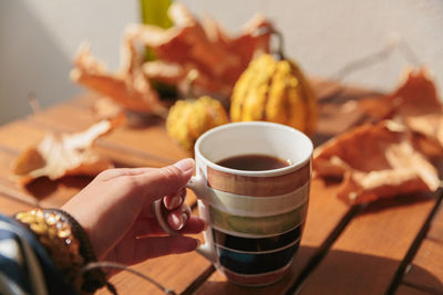 Cropped hand of woman holding coffee on table