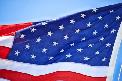 Low angle view of us  flag against blue sky