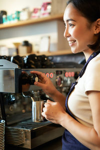 Side view of young woman holding coffee in gym