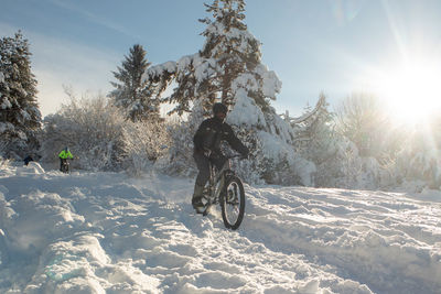 Man riding bicycle on snow covered landscape