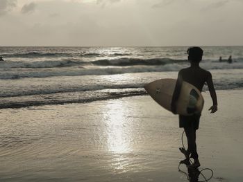 Full length of shirtless man on beach against sky