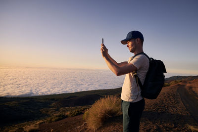 Full length of young woman standing against sky during sunset