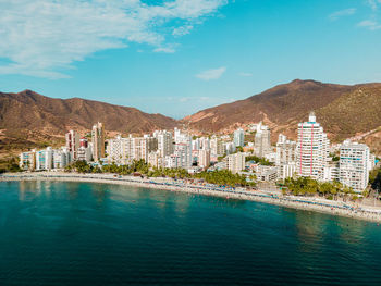 Buildings by sea against sky