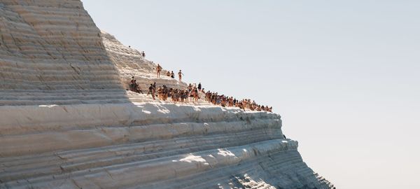 People enjoying on rock formation against clear sky