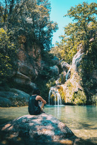 Man sitting on rock by lake