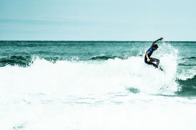 Man surfing in sea against sky