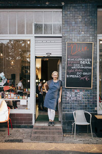 Portrait of female owner standing at entrance of deli