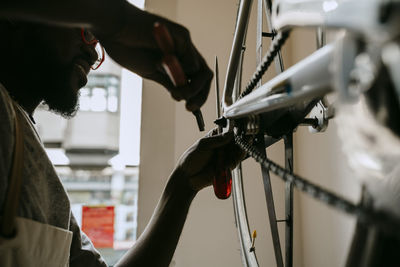 Owner with hand tool repairing bicycle in workshop