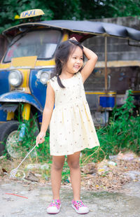 Full length portrait of smiling girl standing outdoors