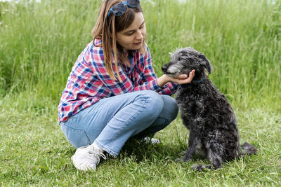 Young woman with dog on grassy field