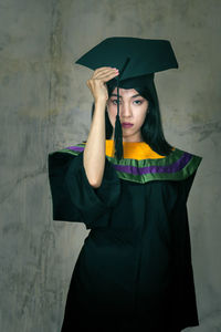 Portrait of young woman standing against wall