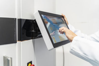 Close-up of technician in lab coat operating 3d printer