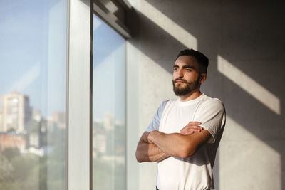 Young man standing against modern wall