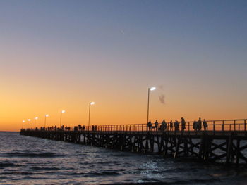 Silhouette pier over sea against clear sky during sunset