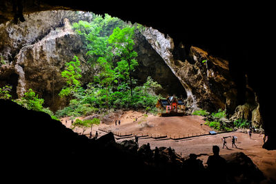 People on cliff by cave