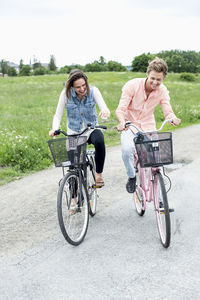 Happy young friends riding bicycles on country road