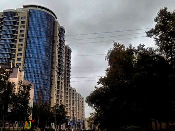 Low angle view of skyscrapers against cloudy sky