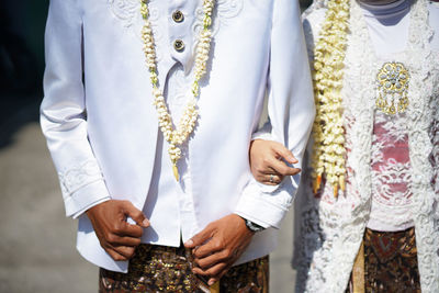 Midsection of bride holding wedding dress