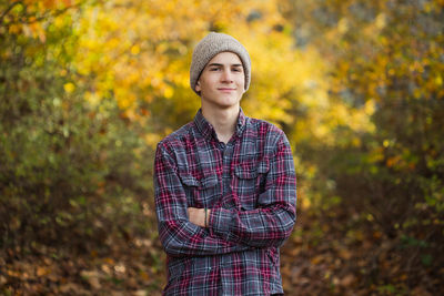Teen boy stands in forest in pacific northwest, confident, smiling.