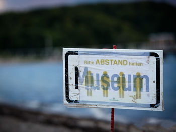 Close-up of information sign against lake
