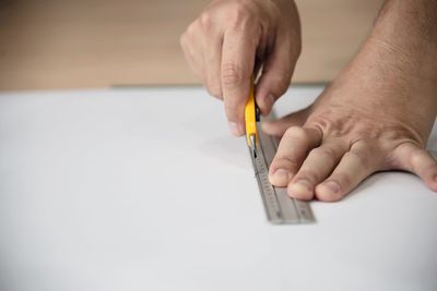 Close-up of man hand holding pencils on table