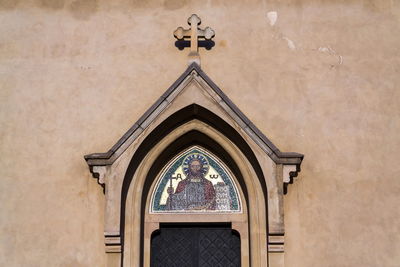 Low angle view of cross on building wall