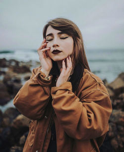 Beautiful young woman with make-up standing by sea during winter