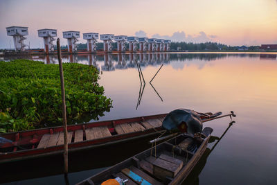 Fishing boat moored at lake against sky during sunset