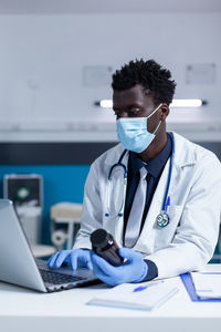 Doctor wearing mask holding medicine bottle