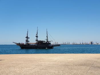 Sailboat in sea against clear blue sky
