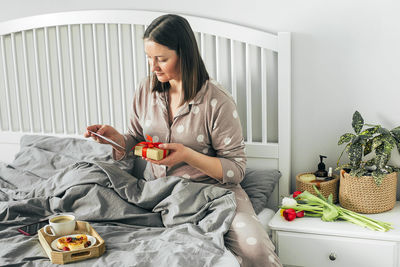 Young woman sitting on bed in bedroom