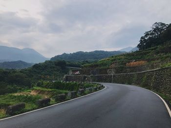 Road by mountains against sky