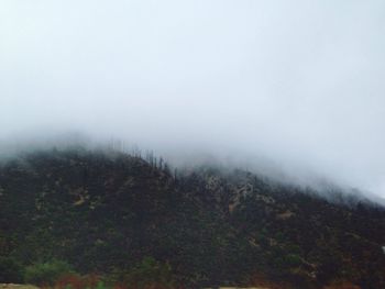 Scenic view of mountains in foggy weather against sky