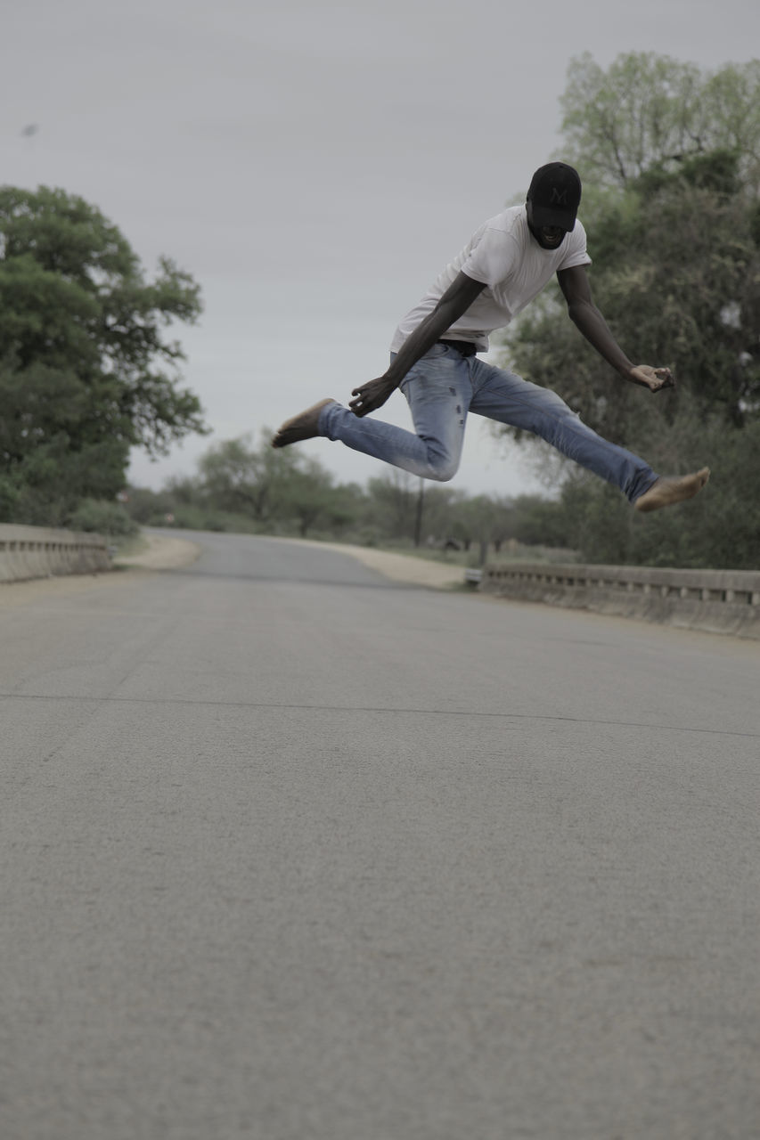 FULL LENGTH OF MAN JUMPING ON ROAD