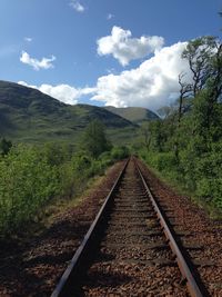 Railroad track against cloudy sky