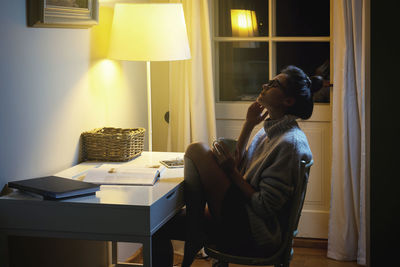 Rear view of woman using laptop at home