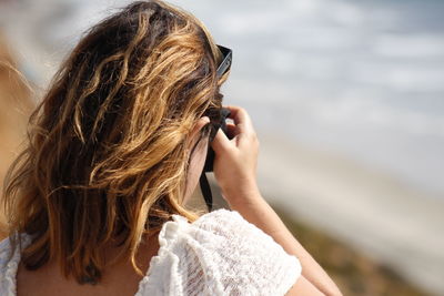 Rear view of woman photographing with mobile phone outdoors