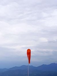 Low angle view of wind sock against cloudy sky