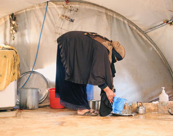 A refugee woman works inside her tent. syrian refugees.