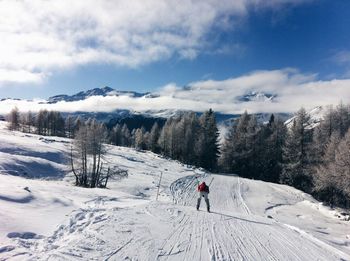 Rear view of person skiing on snowcapped mountain against sky