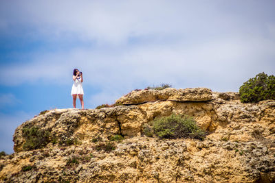 Woman standing on rock against sky