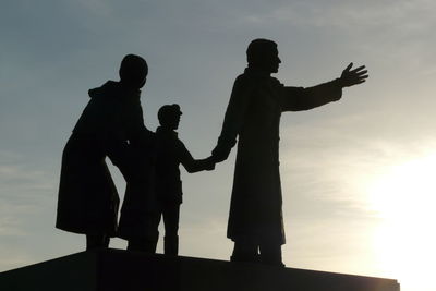 Silhouette man with arms raised standing against sky