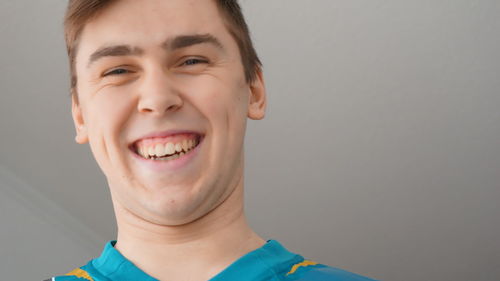 Close-up portrait of cheerful young man against ceiling