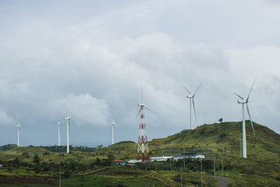 Windmills on field against sky