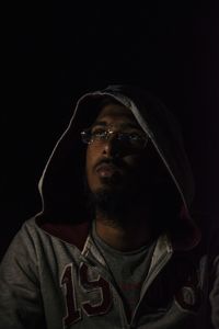 Portrait of young man looking away against black background