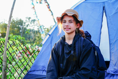 Woman backpacking sitting beside tent camping alone on vacation and mountain behind her