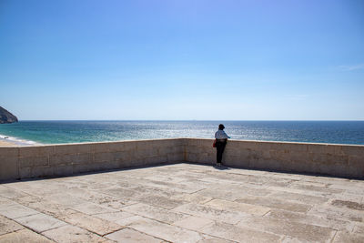 Rear view of man standing by sea against sky