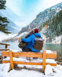 Rear view of man sitting on snow covered mountain