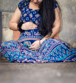 Young pregnant women showing her round belly womb with hand from different angle